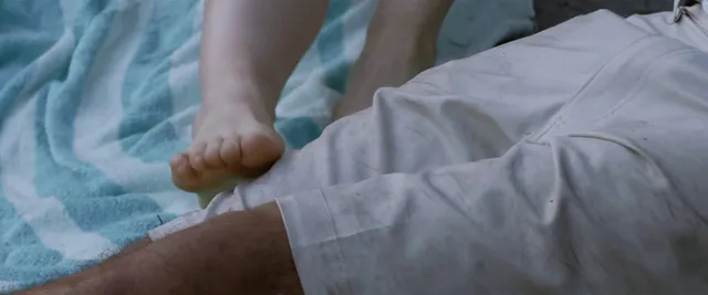 Willa Fitzgerald resting a bare foot on bedding in a scene.