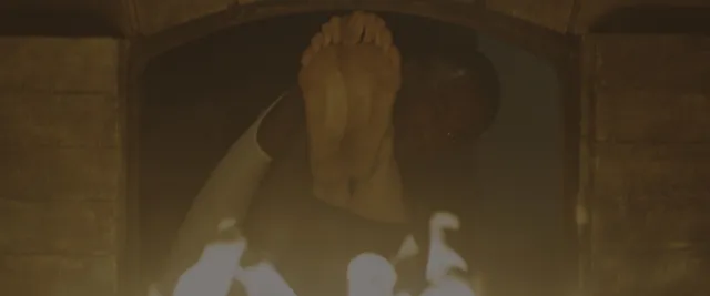 Margaret Qualley a dimly lit screen detail of raised bare soles.