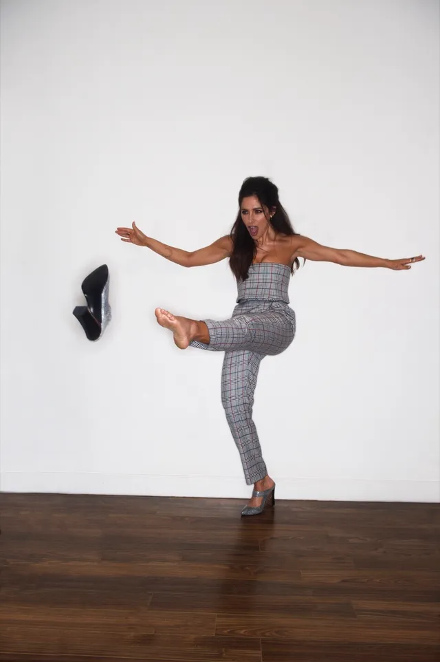 Sarah Shahi posing with one leg raised during a studio portrait.