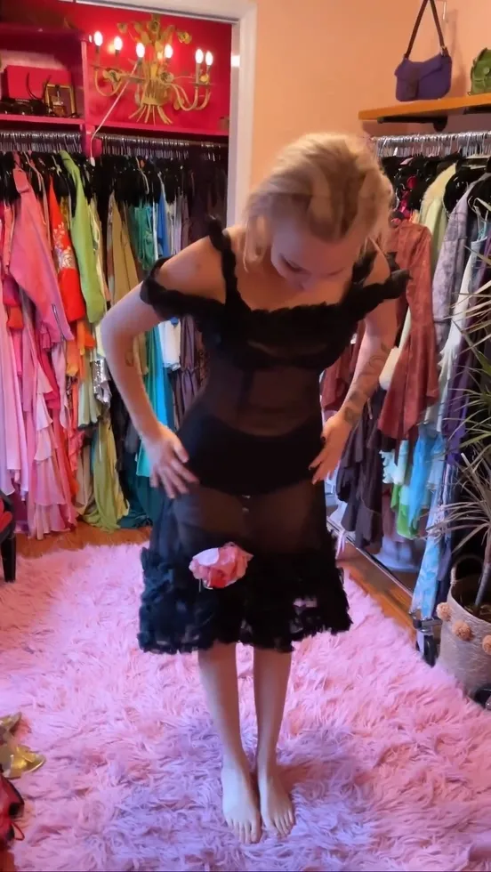 Grace VanderWaal trying on a black dress inside a clothing shop.