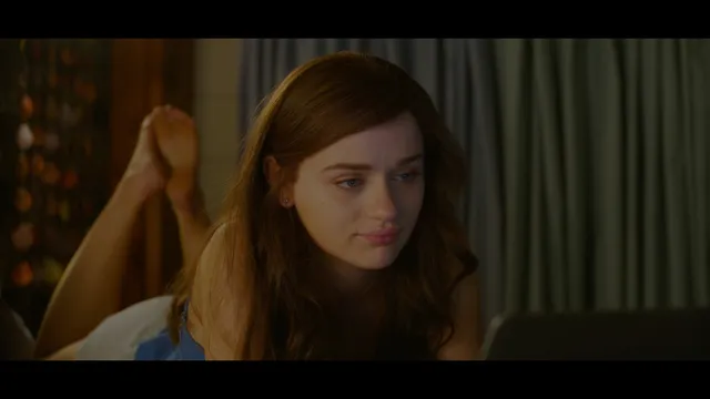 Joey King lying with her bare feet raised behind her in a film scene.