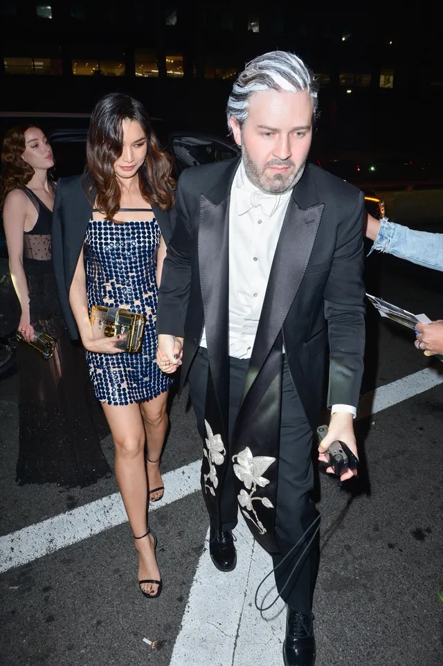 Gemma Chan walking beside a man at an evening event.