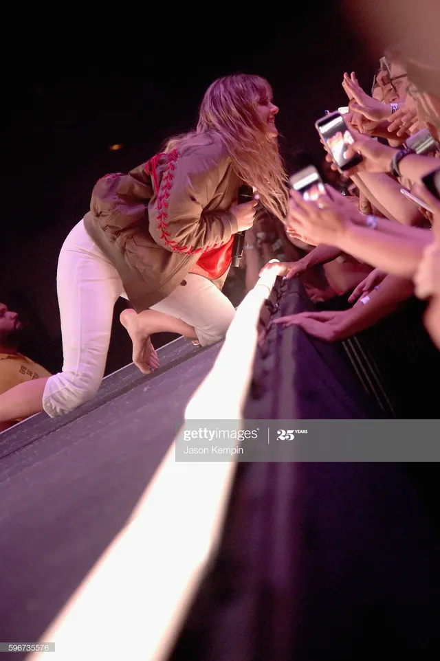 Tove Lo kneeling barefoot near fans at the front of a stage.