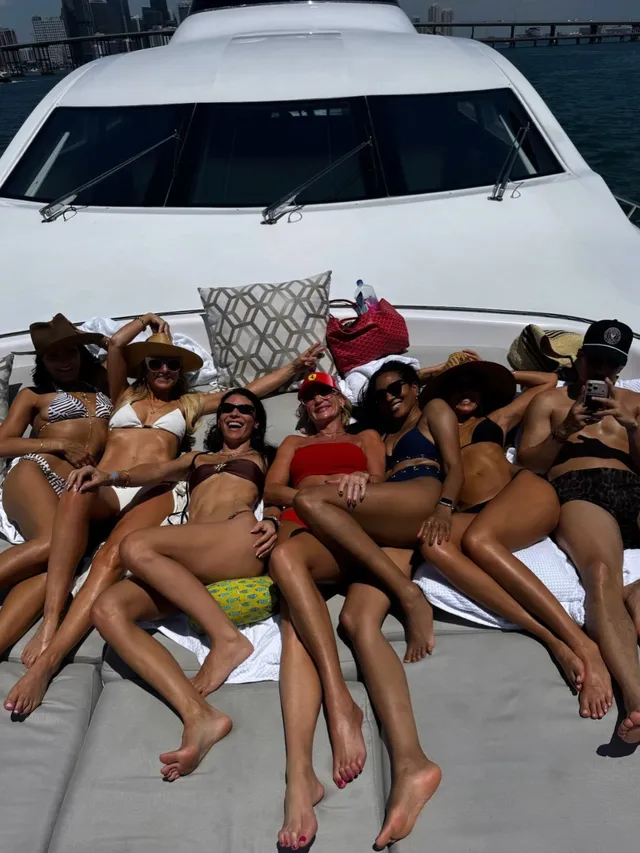 Jessica Alba sitting barefoot with a group on a boat.