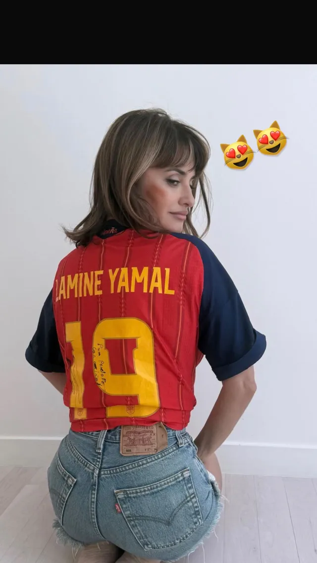 Penélope Cruz wearing a football shirt and denim shorts.