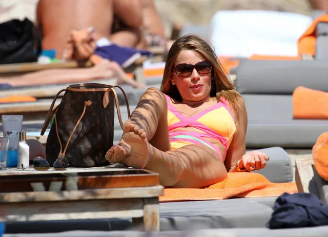 Sofía Vergara reclining on a lounger with one bare foot raised.