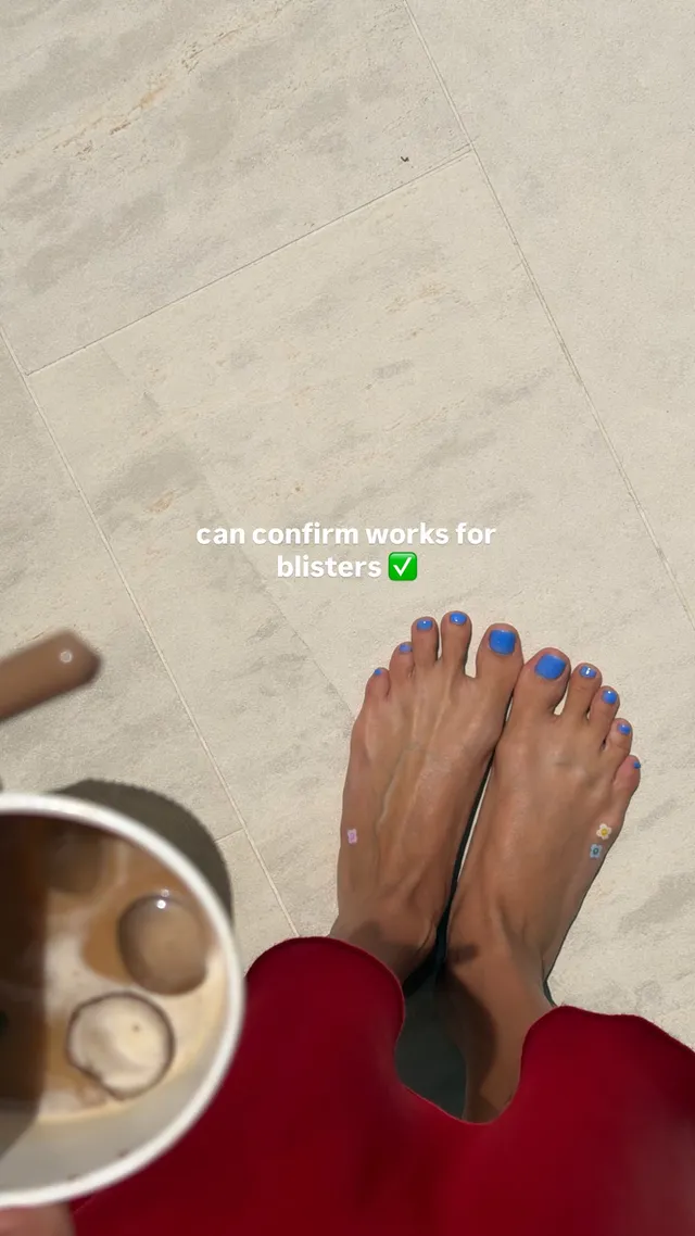 Hailey Bieber showing bare feet with blue toenail polish.