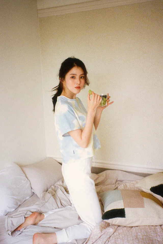 Han So-hee kneeling barefoot on a bed.