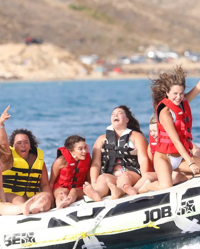 Madison Pettis sitting barefoot with friends on an inflatable water ride.