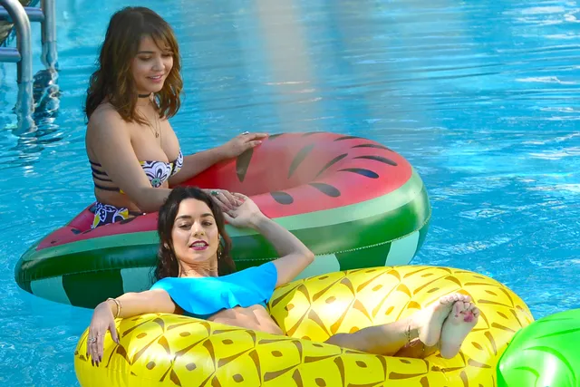 Vanessa Hudgens floating in a swimming pool with bare feet raised.
