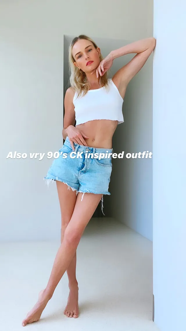 Kate Bosworth posing beside a wall in denim shorts.