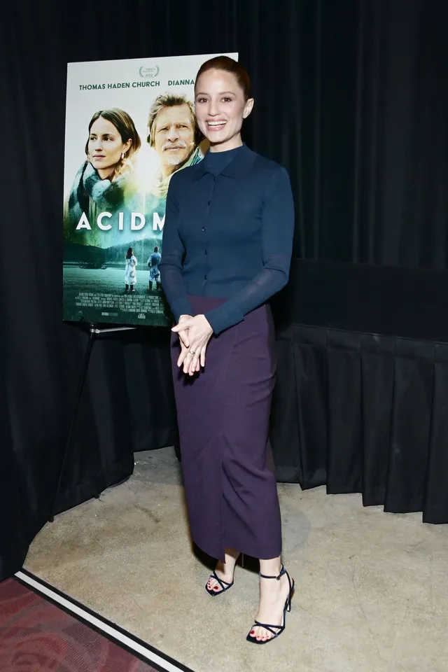 Dianna Agron posing at a screening in a dark top and skirt.