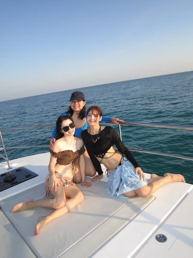 Lisa (Lalisa Manobal) kneeling barefoot on a boat deck with companions.