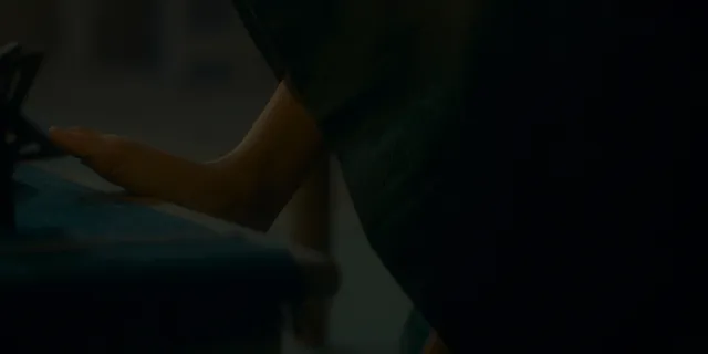 Olivia Cooke resting a bare foot beside candles in a scene.