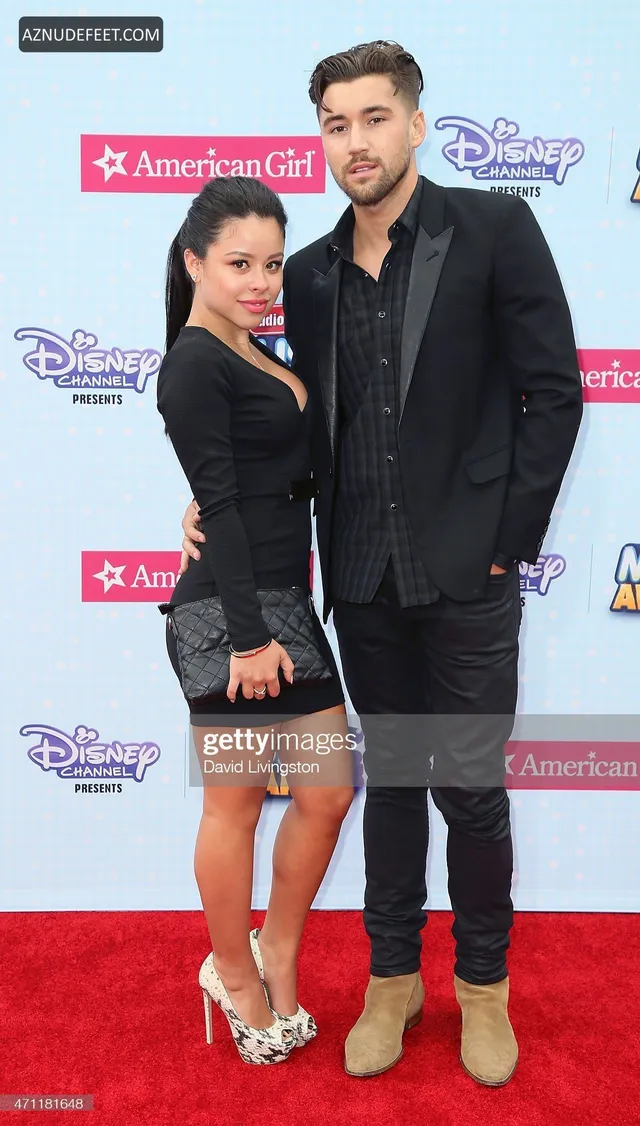 Cierra Ramirez in a black outfit and pale heels beside a companion at a music awards event.