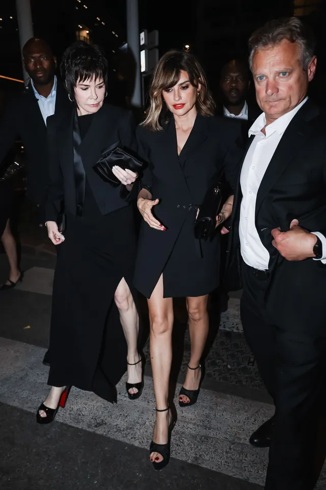Penélope Cruz walking at night in a dark coat and heels.