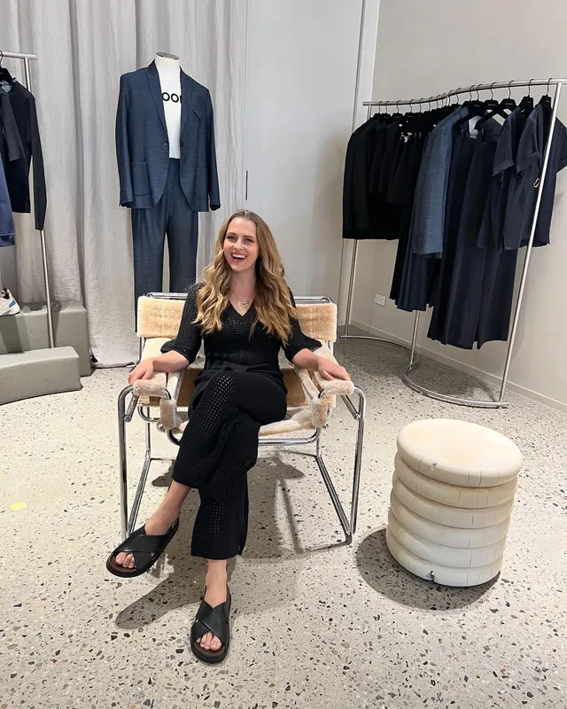 Teresa Palmer sitting in an armchair in a dark outfit.