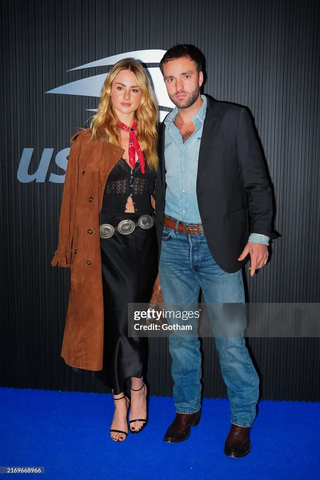 Grace Van Patten standing with a man in a brown coat and black heels.