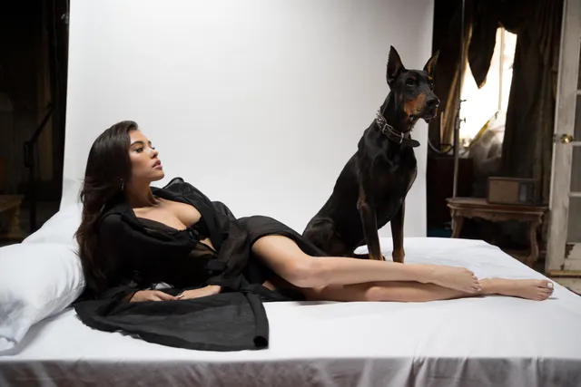 Madison Beer: reclining barefoot beside a dog on white bedding.