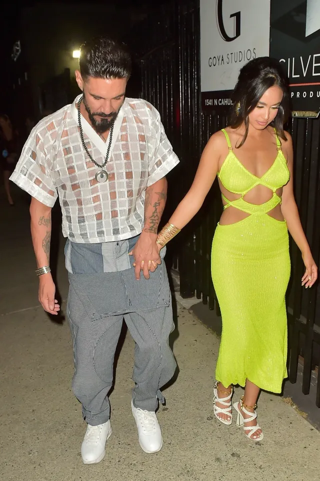 Emily Tosta walking in a yellow dress and white heels.