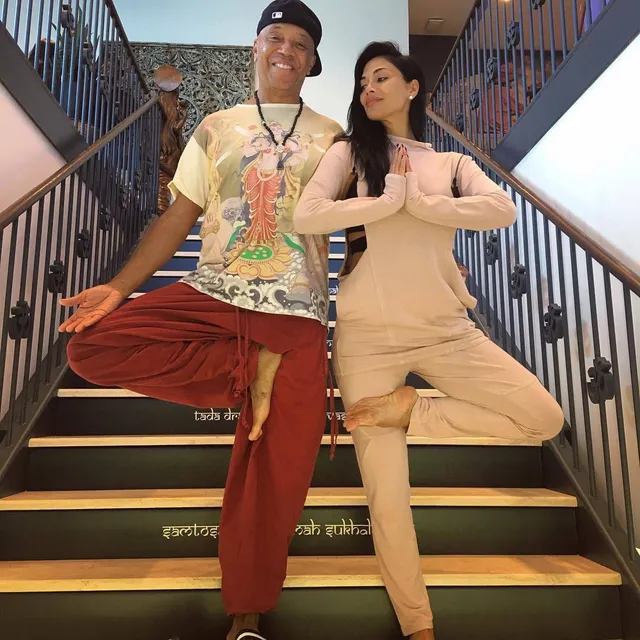 Nicole Scherzinger balancing barefoot on stairs beside another person.