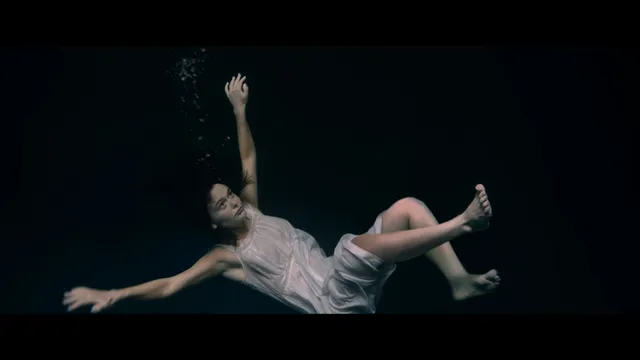 Emily Alyn Lind shown floating underwater in a pale dress in a scene.