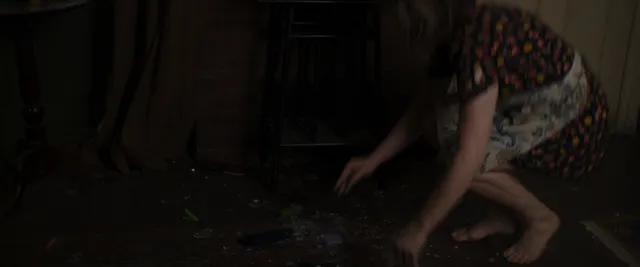 Chloë Grace Moretz crouching barefoot indoors in a screen image.