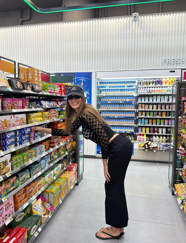 Hailey Bieber posing in flip-flops in a shop aisle.