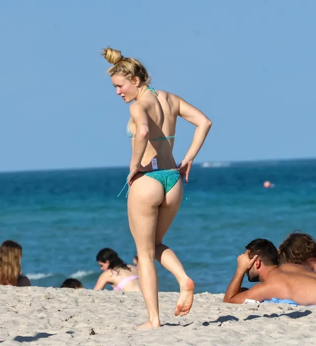 Zara Larsson walking barefoot along a beach.