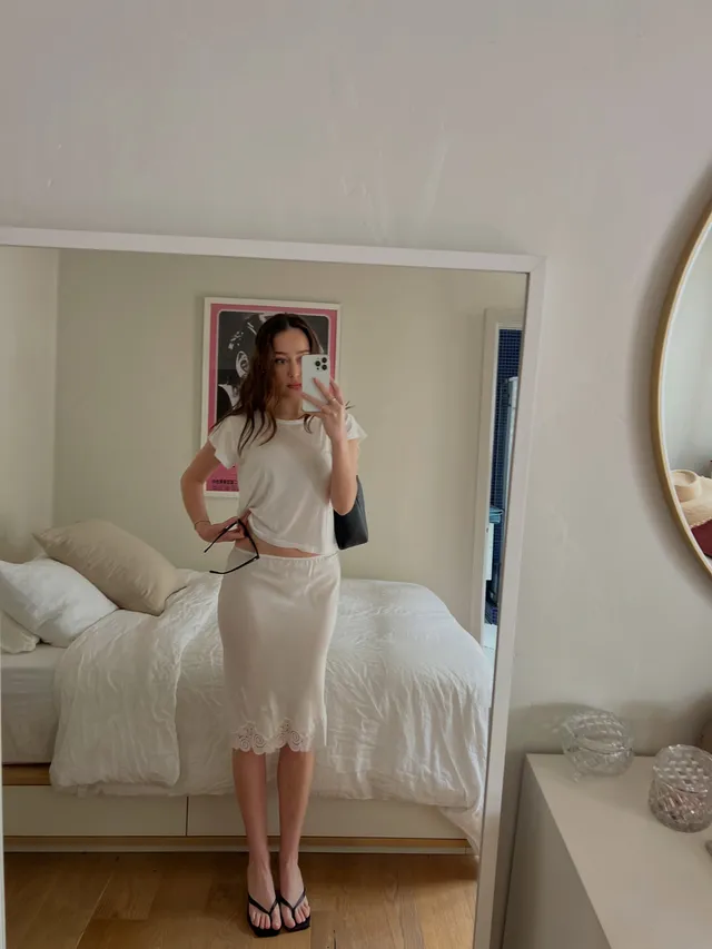 Alycia Debnam-Carey taking a mirror portrait in a pale outfit and flip-flops.