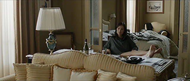 Olivia Wilde reclining on a bed in a film scene.