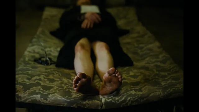 Emma Stone lying on a bed with the soles of her bare feet toward the camera.