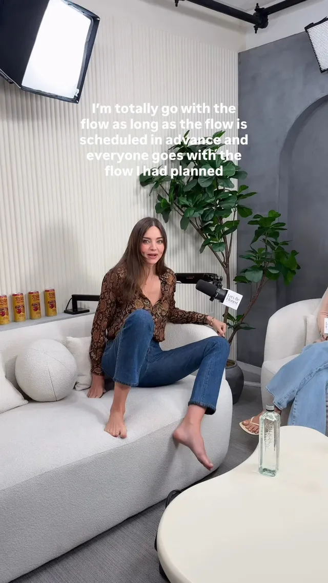 Miranda Kerr a patterned top and jeans on a pale sofa.