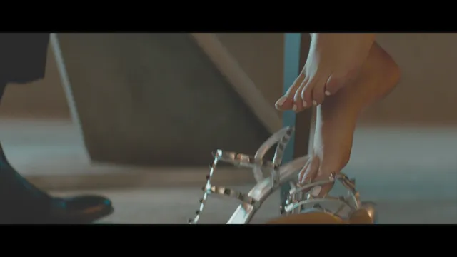 Kristen Stewart wearing metallic strappy heels in a screen image.