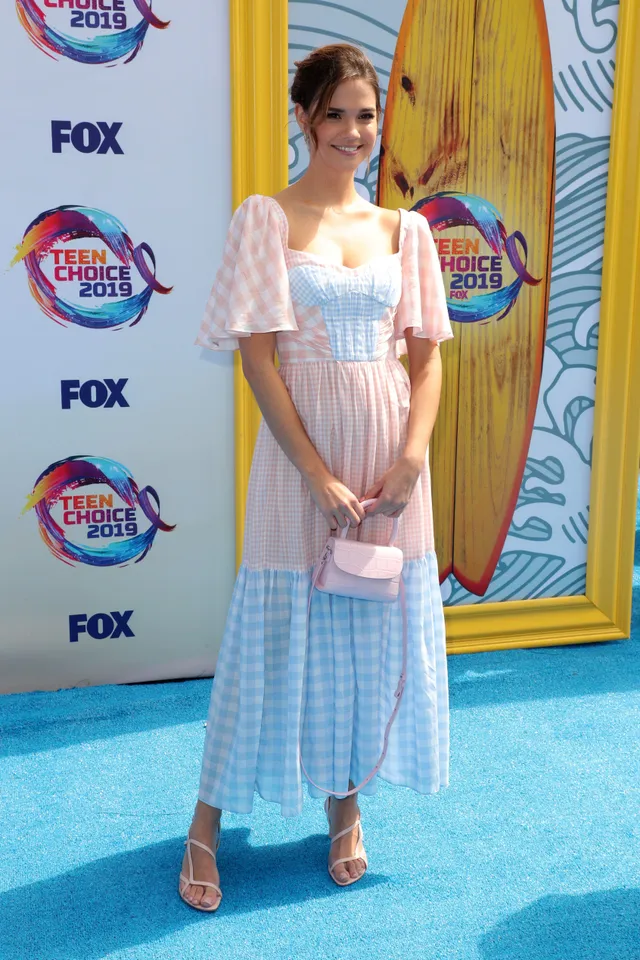 Maia Mitchell wearing a pastel dress and heels at an event.