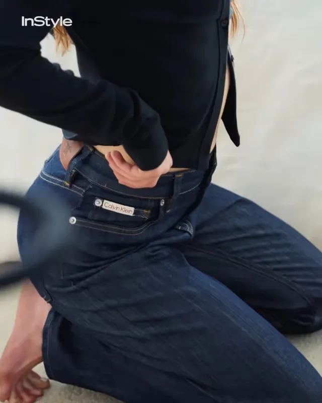 Sadie Sink sitting barefoot in jeans during a photo shoot.