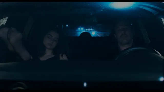 Ana de Armas sitting in a car beside a companion.