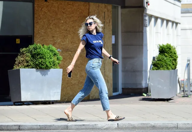 Vanessa Kirby walking outdoors in jeans and flat sandals.
