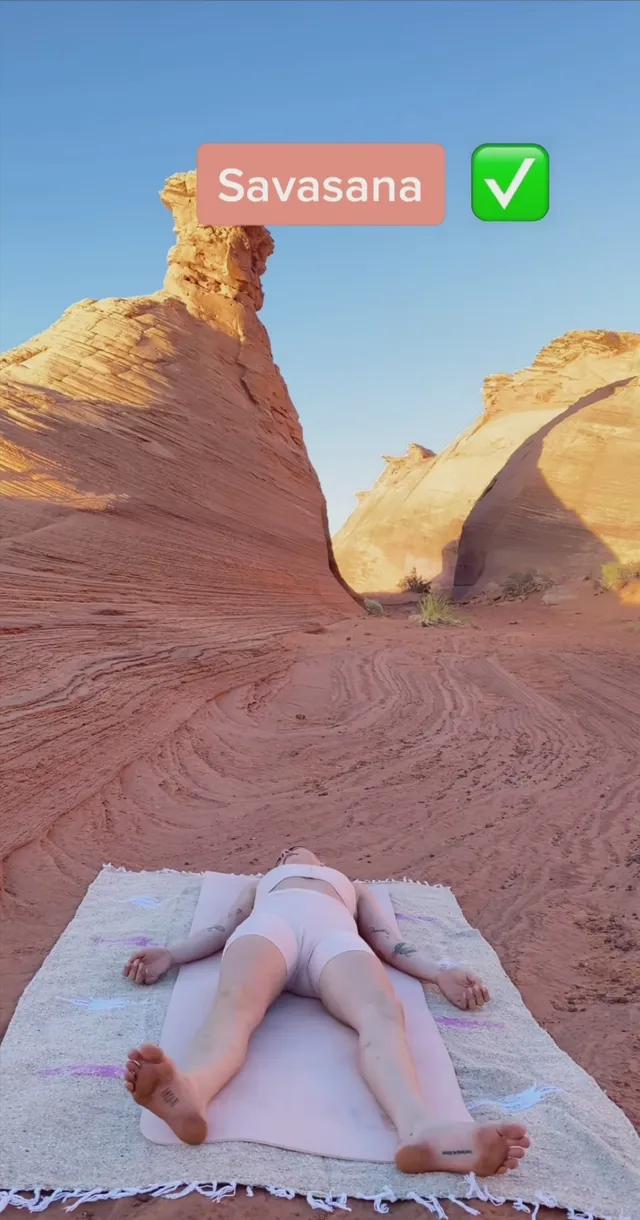 Cara Delevingne lying on a blanket in a desert landscape.