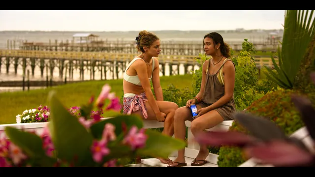 Madison Bailey sitting beside another woman outdoors in a scene.