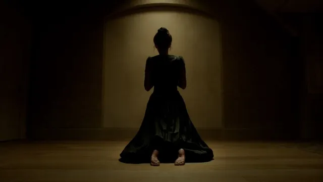 Eva Green kneeling barefoot in a long black dress.