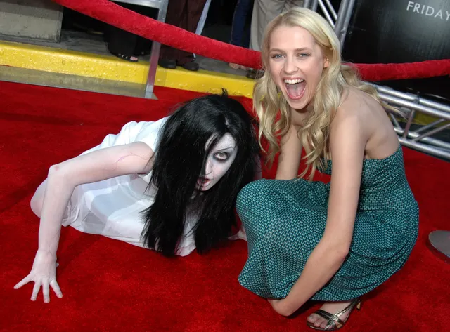 Teresa Palmer posing with a costumed performer on a red carpet.