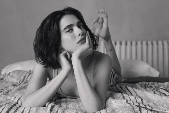 Margaret Qualley a monochrome portrait lying across a bed.