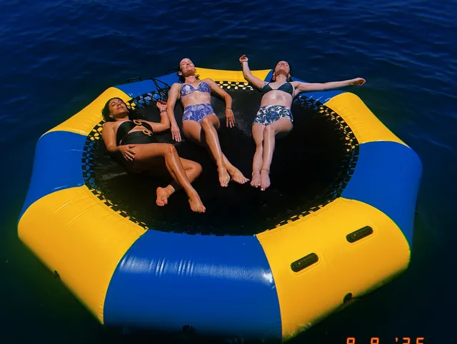 Anna Kendrick relaxing barefoot on an inflatable with other adults.