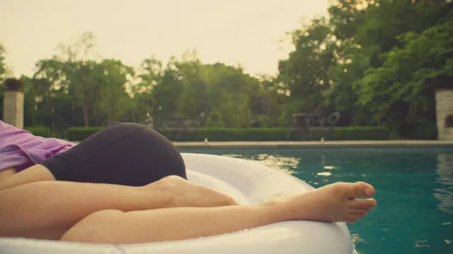 Odessa A'zion reclining barefoot on a swimming pool float in a scene.