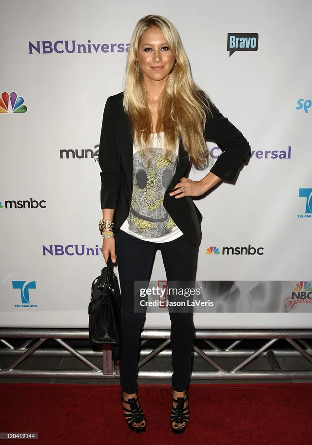 Anna Kournikova wearing lace-up black heels with dark trousers and a pale blouse.