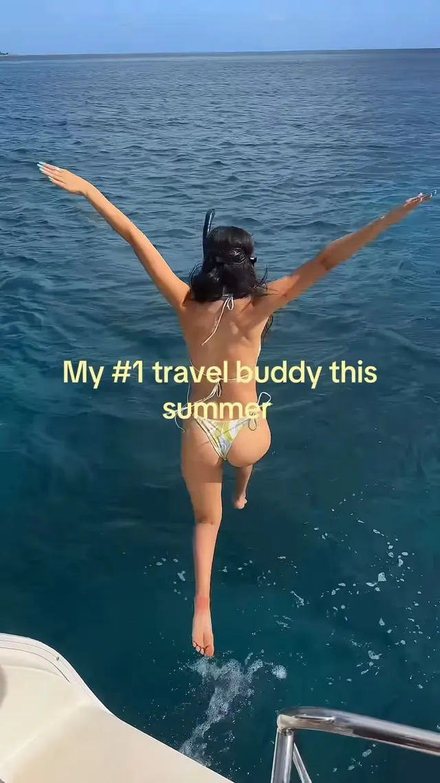 Victoria Justice jumping from a boat toward blue water.