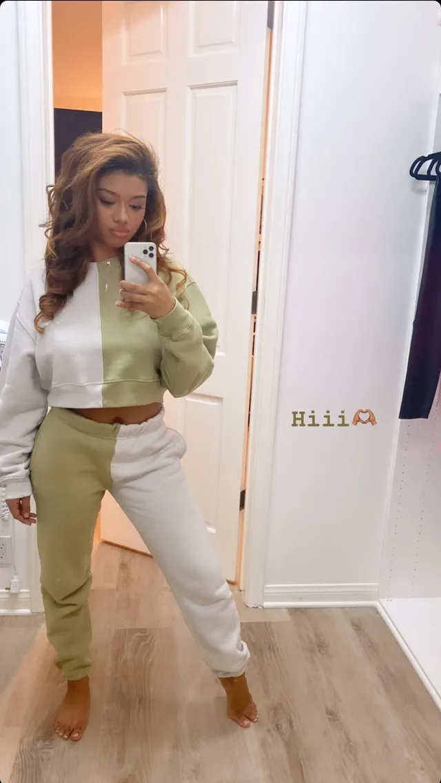 Sierra Capri standing barefoot in a two-tone tracksuit in front of a mirror.