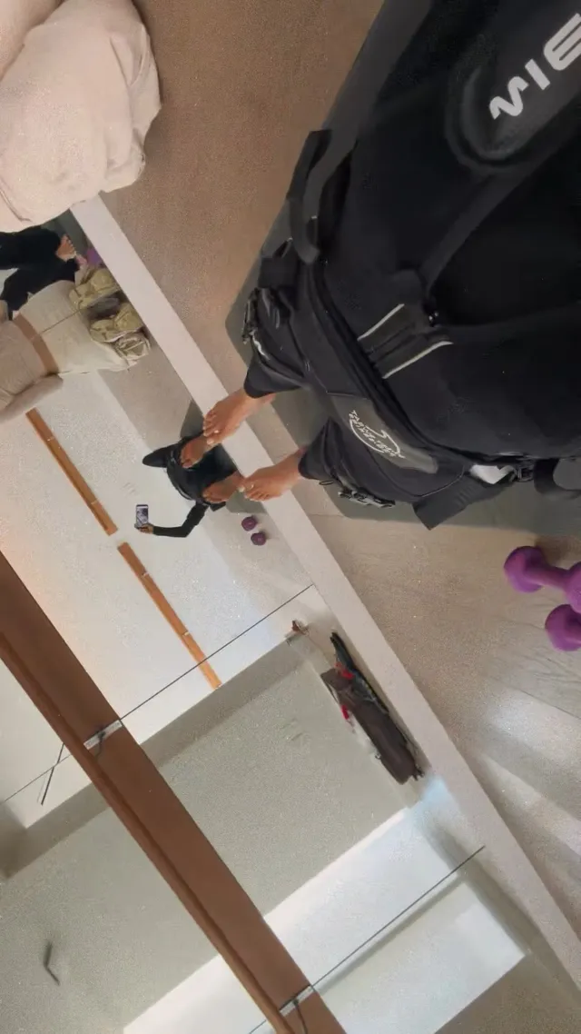 Shay Mitchell taking a casual mirror portrait in dark clothing and socks.