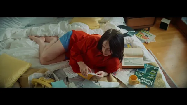 Billie Eilish a reclining red-shirt screen scene.